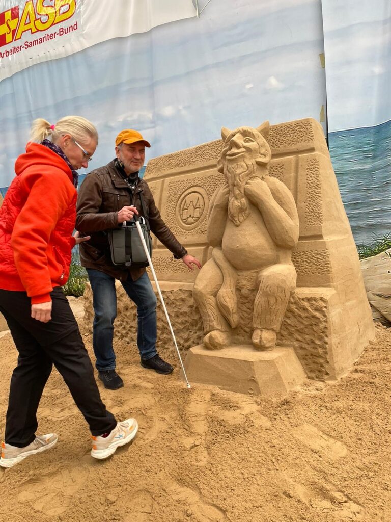 Foto: J. Trinkus nähert sich dem kleinen Sand-Teufel, der im Original vor der Lübecker Marienkirche sitzt