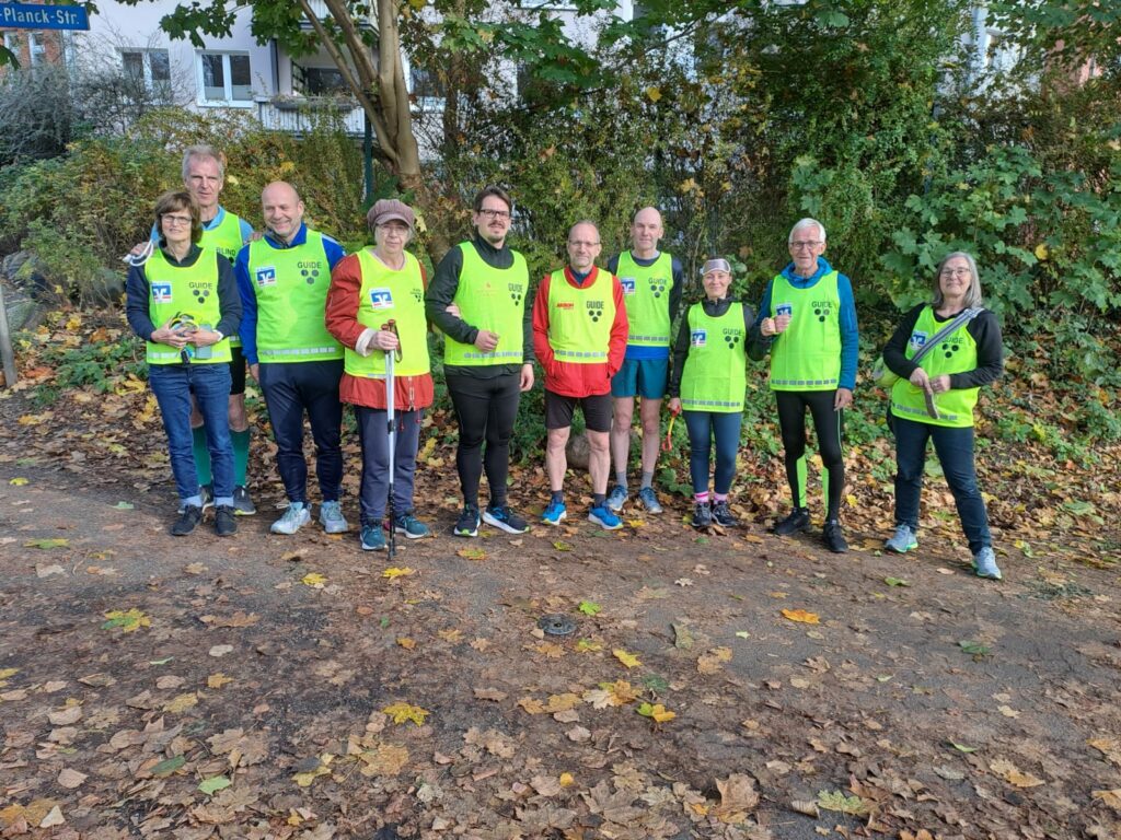 Eine Gruppe von 10 Tandemläuferinnen und -läufer in gelben Westen